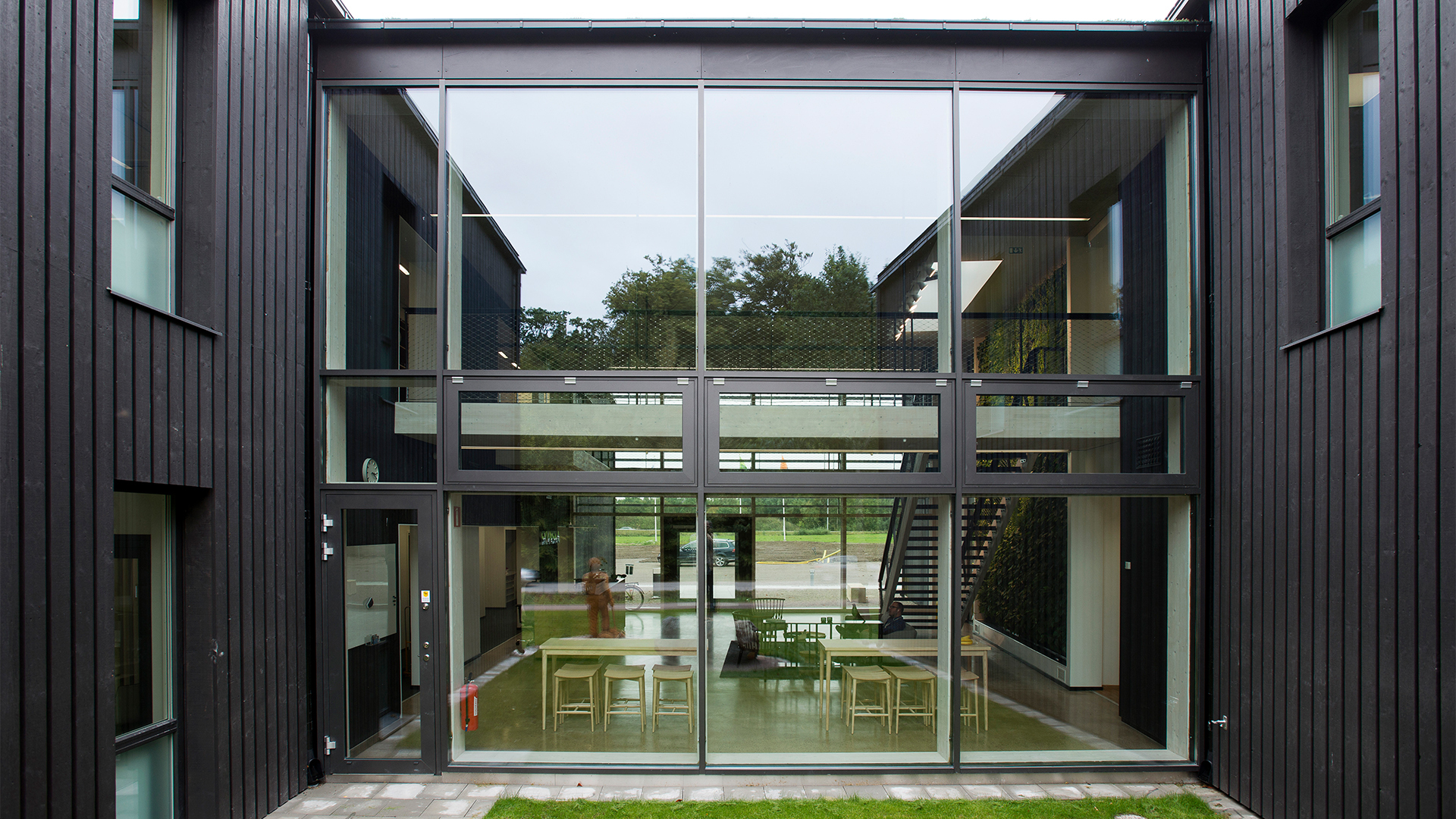 Väla Gårdin toimistorakennuksen lasijulkisivu, sisällä neuvottelualue ja portaikko.